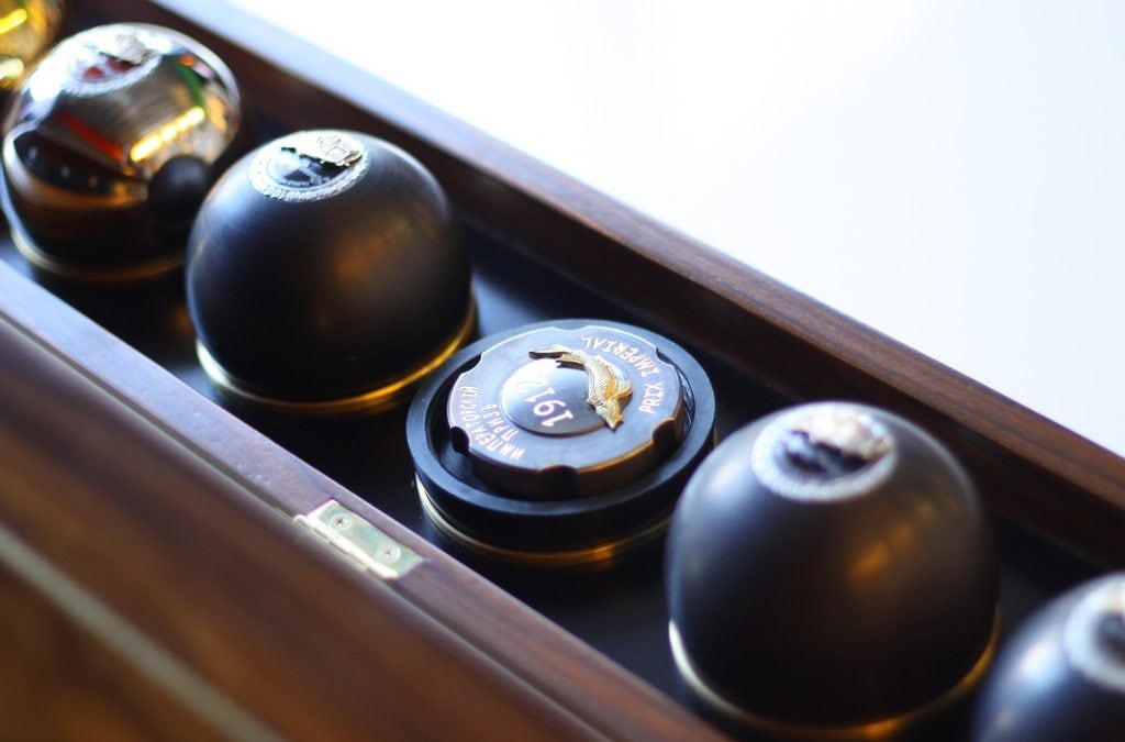 Close-up of RussoBaltique caviar spheres and a crested gold lid in their walnut case