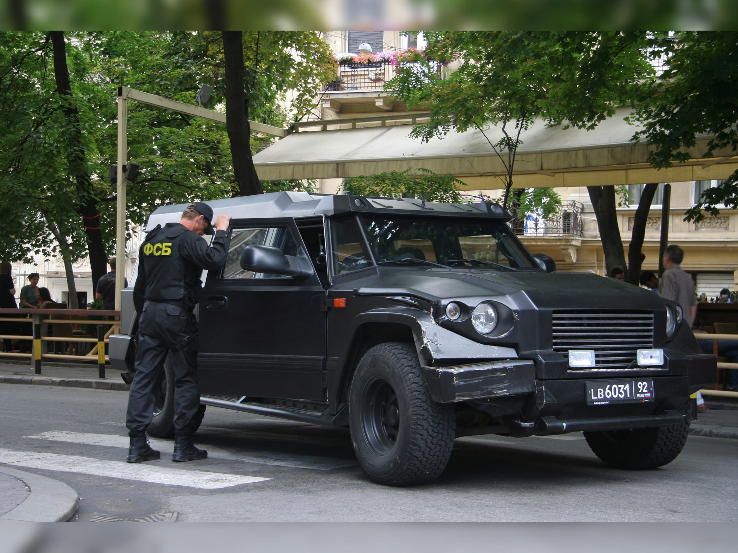 Armed actor in black beside a black DARTZ Prombron’ on a film set