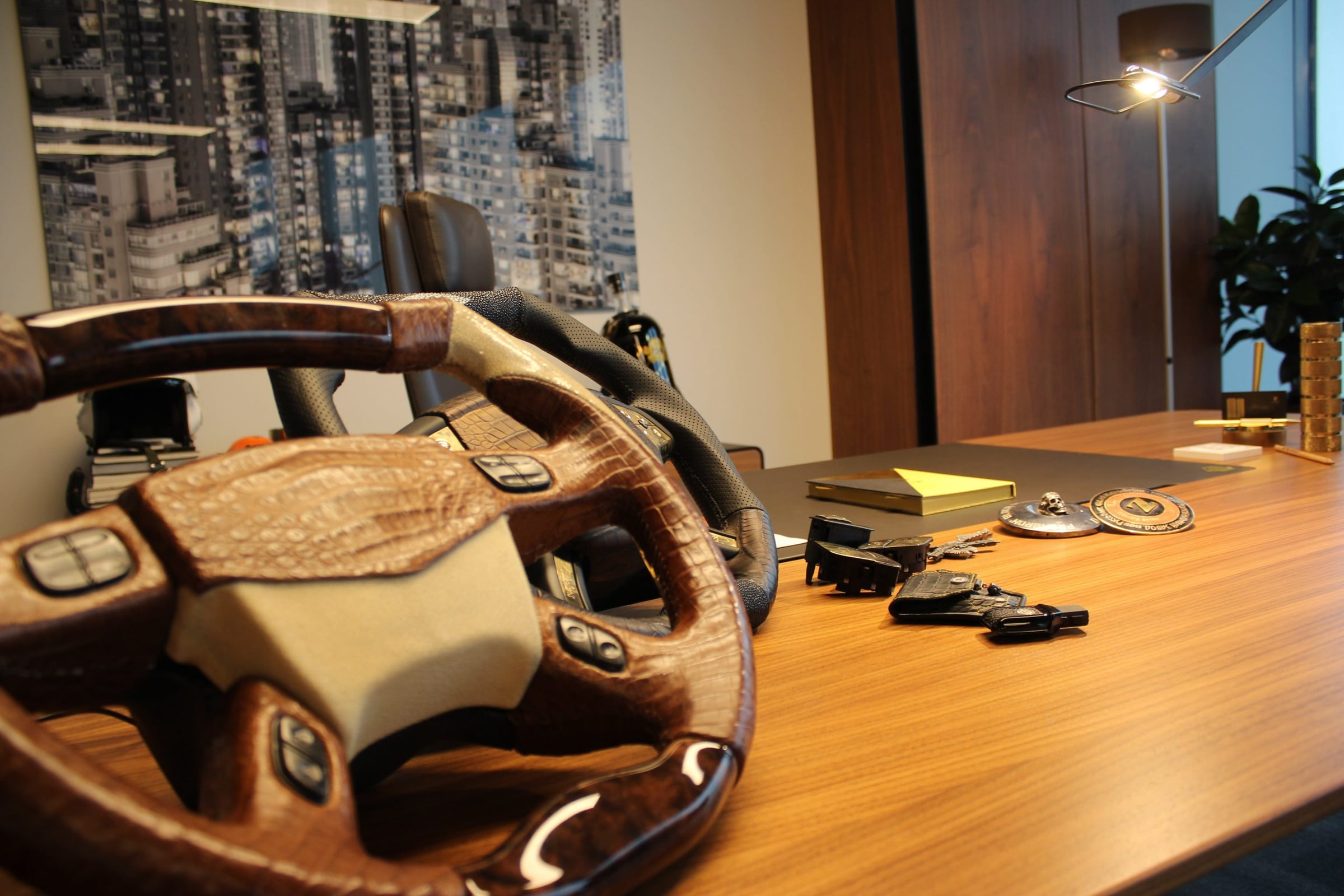 Crocodile-leather steering wheel and gold trim samples on a studio desk