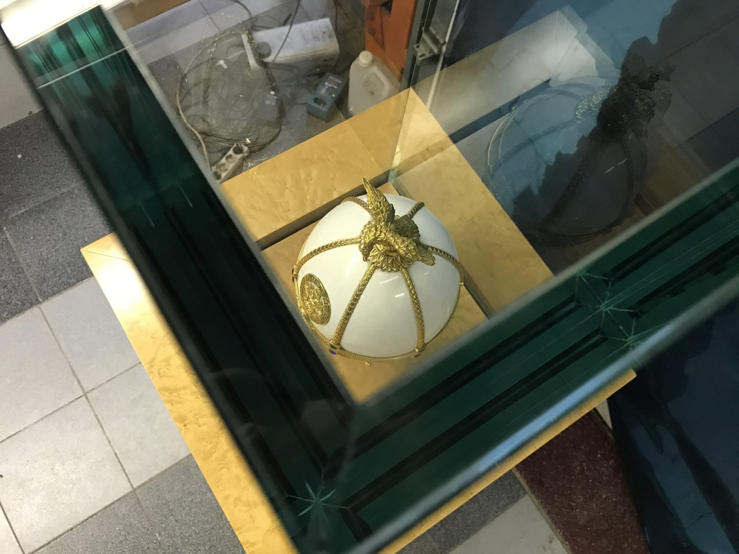 Jewelled white egg in a gold-framed glass vitrine