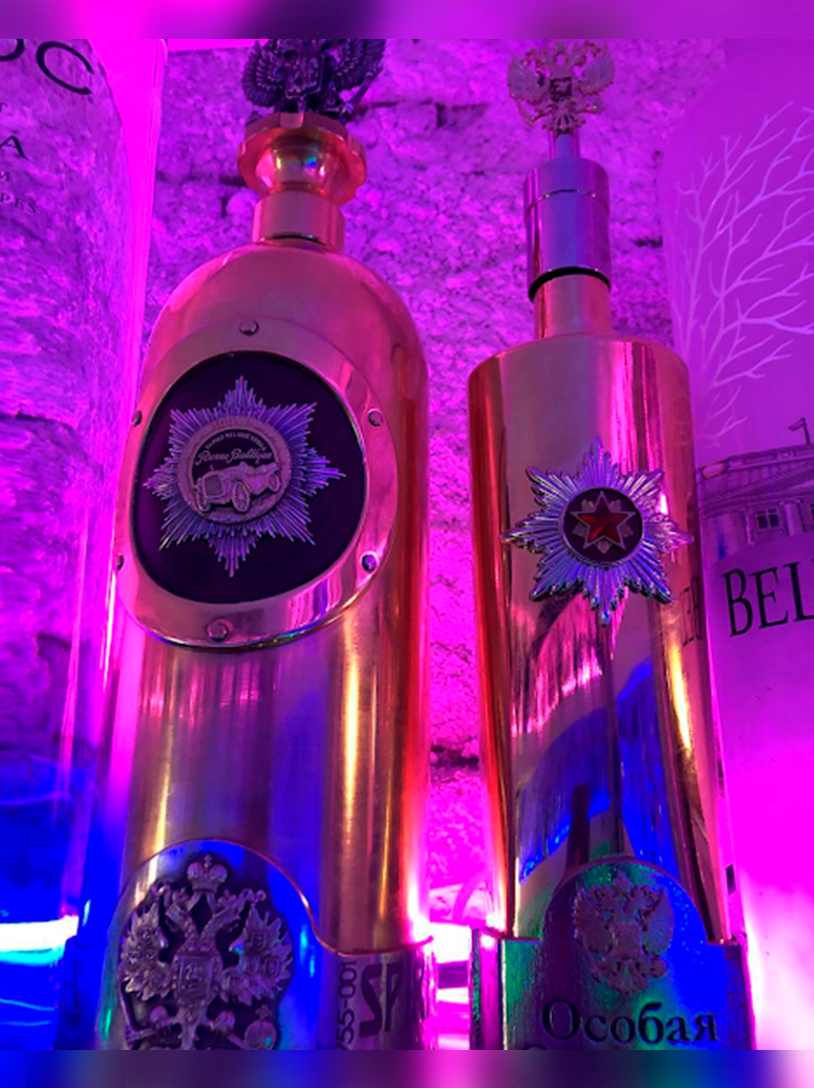 Gold DARTZ RussoBaltique vodka bottles under pink bar lights
